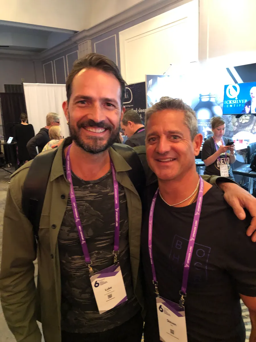 Steven arm in arm with a friend on a conference floor